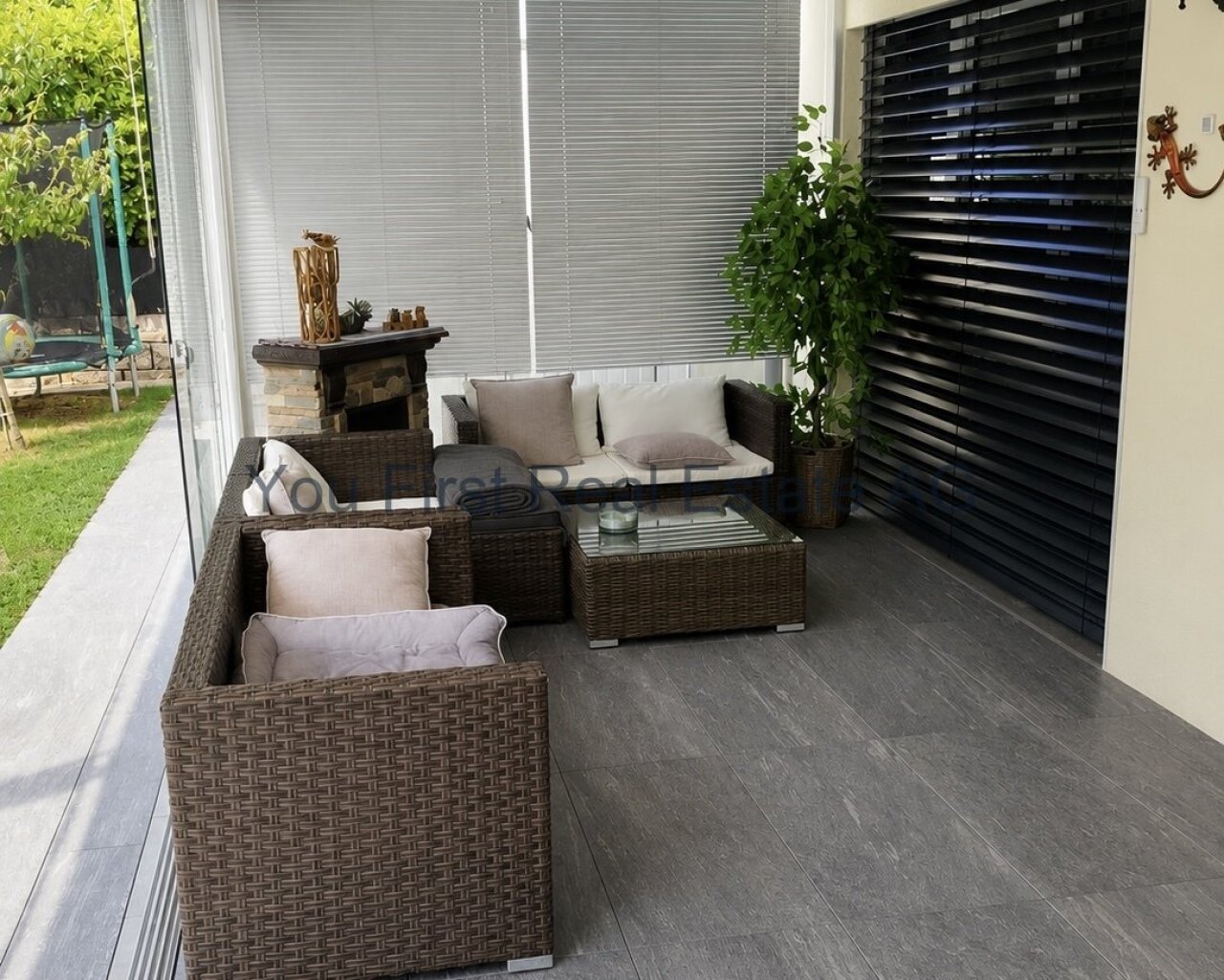 Überdachte Terrasse mit Schiebetüren und Natursteinbelag