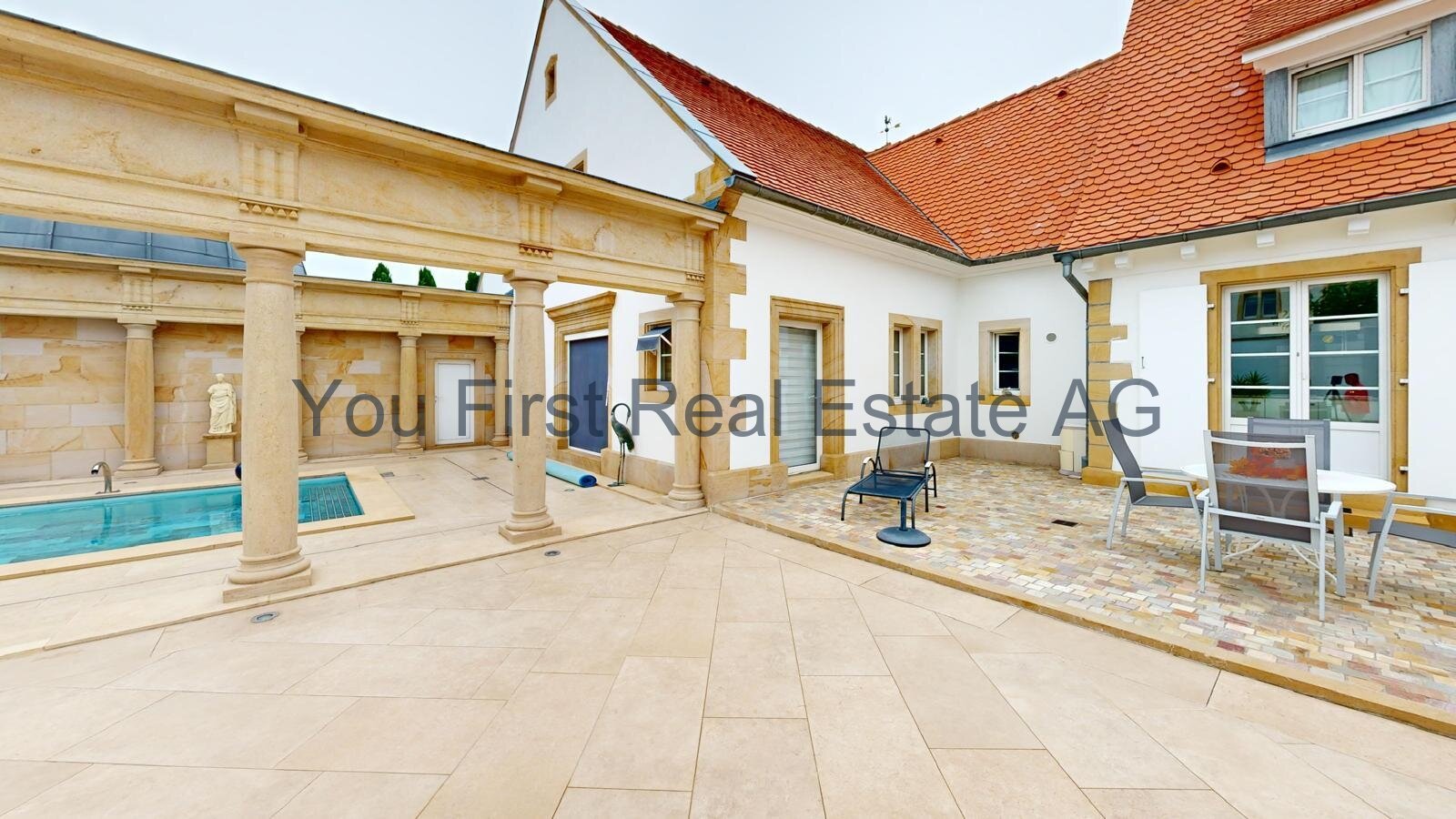 Überdachte Innenhofterrasse mit Säulengang und Poolhaus