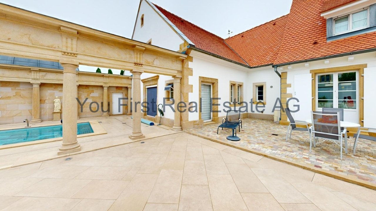 Überdachte Innenhofterrasse mit Säulengang und Poolhaus