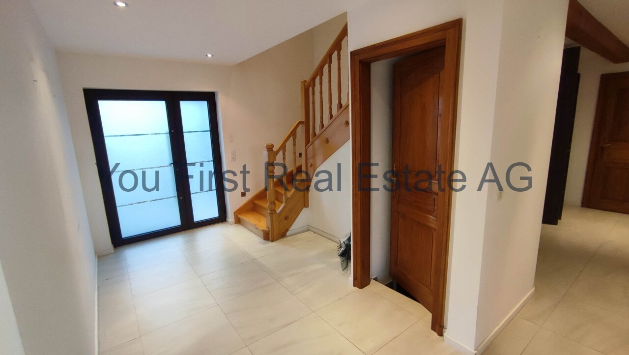 Lichtdurchfluteter Eingangsbereich mit eleganter Holztreppe und hochwertiger Verglasung