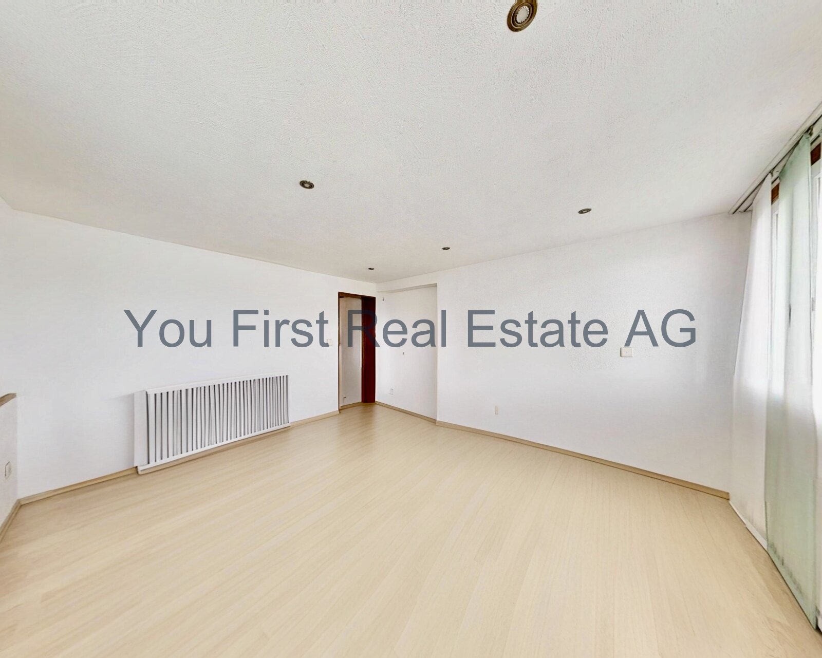 Lichtdurchflutetes Zimmer mit Design-Heizkörper und elegantem Parkettboden