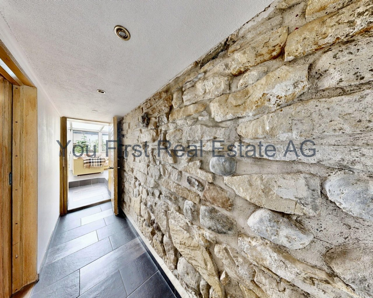 Authentischer Flurbereich mit rustikaler Natursteinwand und modernem Deckenfinish