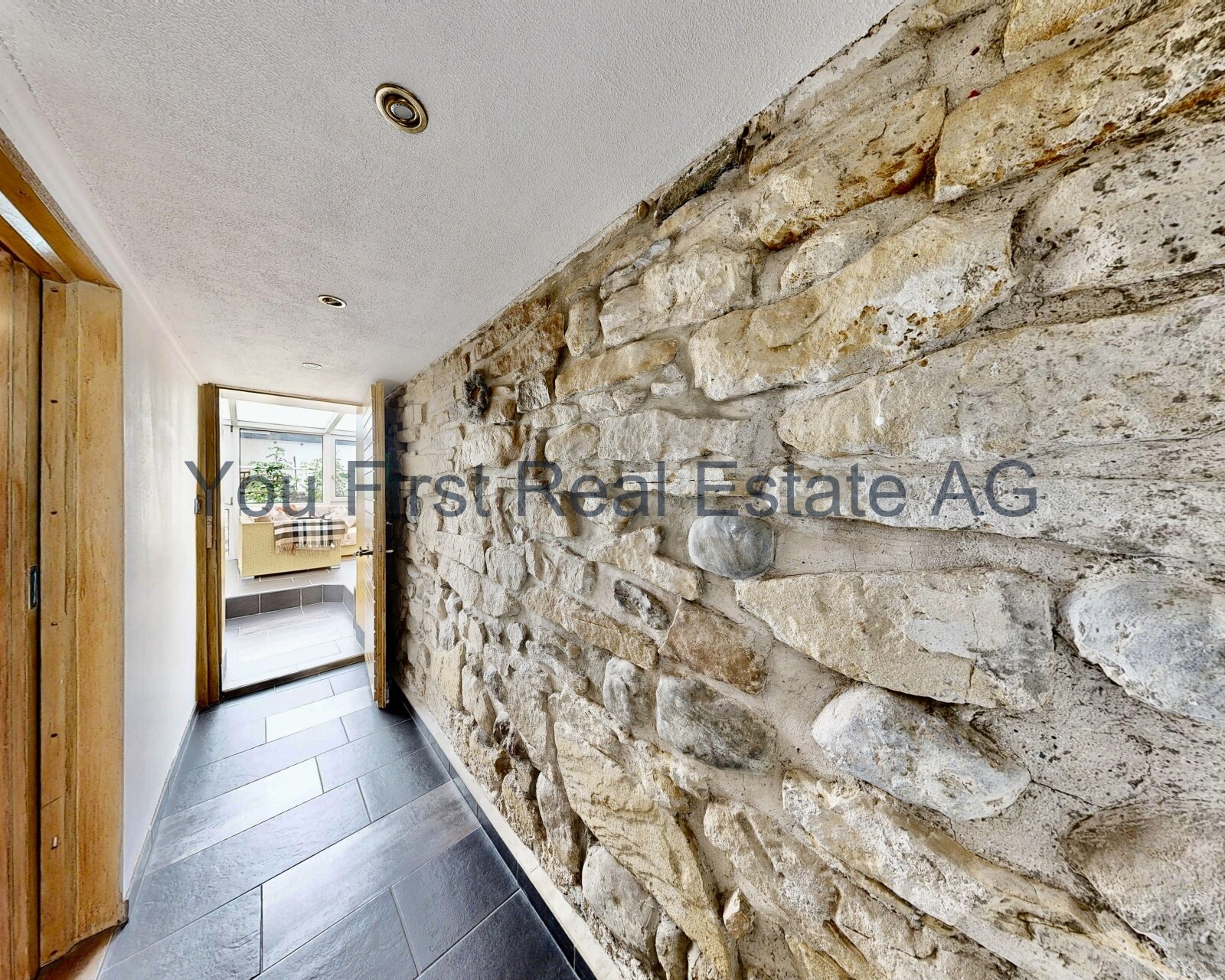 Rustikaler Naturstein-Charme trifft moderne Architektur - Exklusiver Wohnflur mit Steinwand und Design-Bodenfliesen