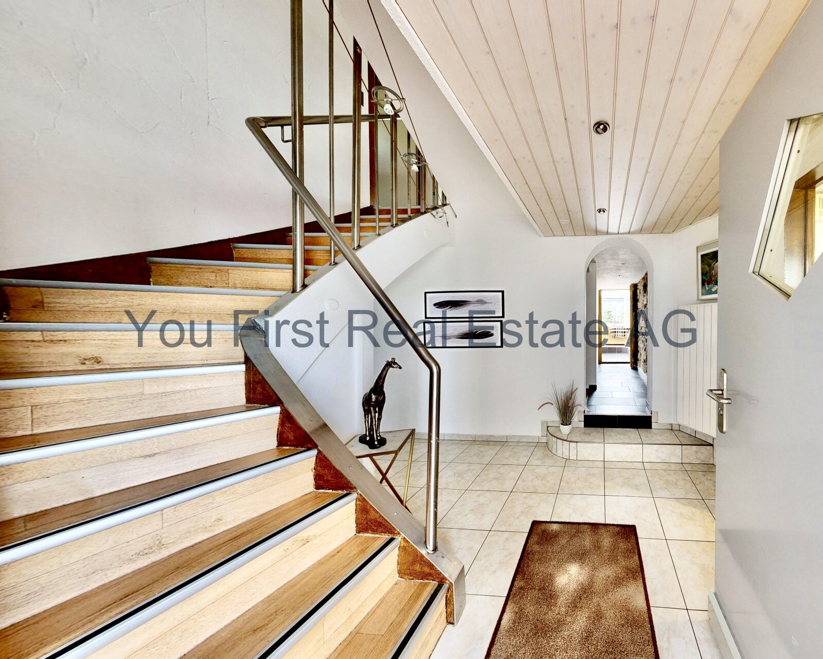 Lichtdurchfluteter Eingangsbereich mit Design-Treppe und elegantem Edelstahl-Geländer