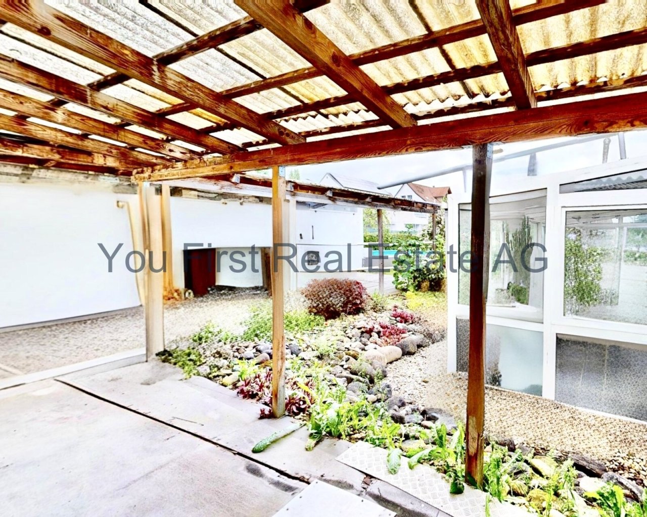 Überdachter Innenhof mit Holzkonstruktion und direktem Gartenzugang