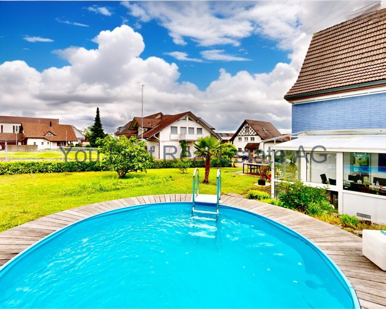Erfrischende Poolanlage mit großzügiger Holzterrasse und Gartenblick