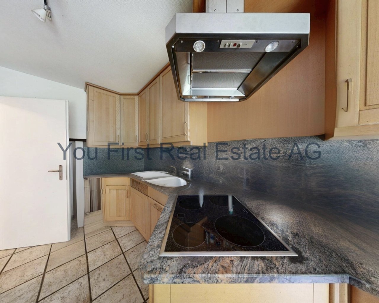 Kompakte Küche mit Naturstein-Arbeitsplatte und Induktionsherd - Effizienz auf kleinstem Raum