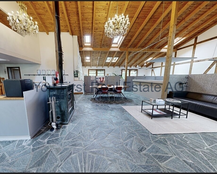 Loft-Ambiente mit Charme: Offene Architektur und elegante Natursteinböden unter imposanten Holzbalken