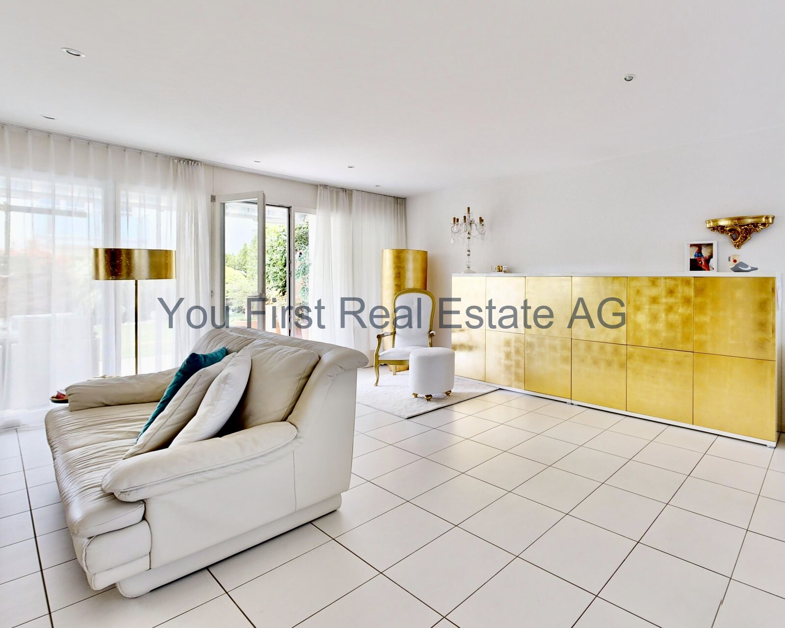 Lichtdurchflutetes Wohnzimmer mit bodentiefen Fenstern und elegantem Goldakzent-Sideboard